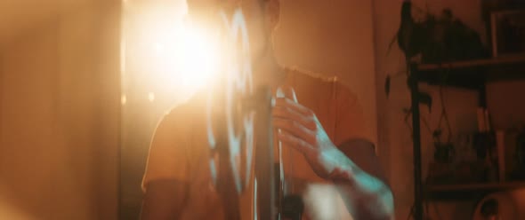 Young man rolling film on vintage projectors reels in bright light alt