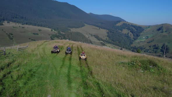 Tourists on Sport Quad Bikes on Beautiful Mountains Background alt