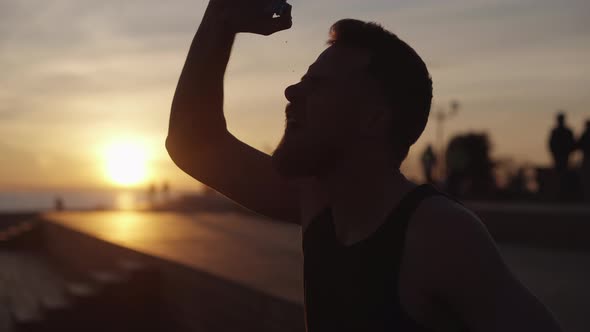 Tired Runner Is Pouring His Head By Water From Bottle After Jog in Evening alt