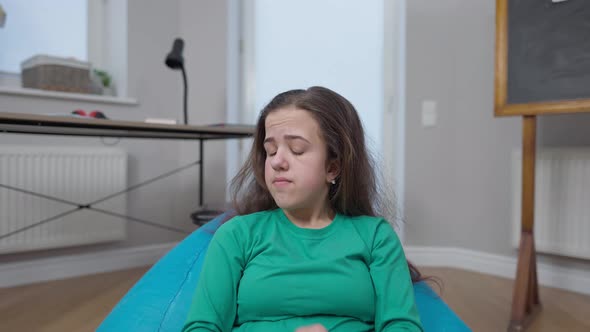 Sad Lonely Little Person Looking Around Crossing Hands Sighing Sitting on Bag Chair in Classroom alt