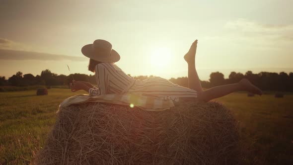 Beautiful girl in a dress lies on a haystack