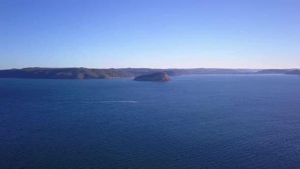 Forward flying over to a dangerous mysterious isolated island oin the middle of wide blue ocean and alt