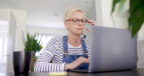 Worried woman sitting at desk looking at laptop