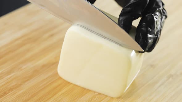 Chef's Hands Cutting Cheese on Wooden Board Preparing Food on Kitchen