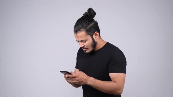 Sad and emotional Indian man chatting with someone using smart phone alt