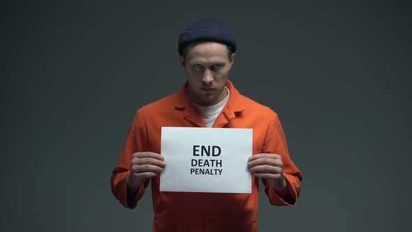 Caucasian Male Prisoner Holding End Death Penalty Sign in Cell, Asking for Help alt