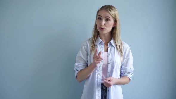 A young, beautiful woman in a blue shirt is actively explaining something alt