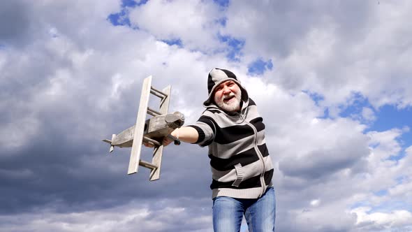 Happy Greybeard Man Imagine Flying on Wooden Plane in Sky Pretend Fly alt