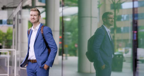 Businessman with backpack waiting in front of urban building