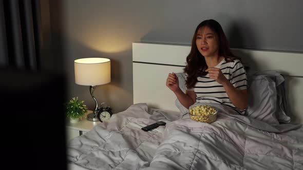 sad young woman watching sport TV and lose a game on a bed at night