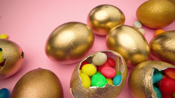 Golden Eggs with Scattered Sweets for Easter on Pink Background