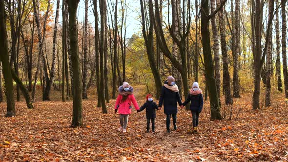 Mother with children in medical masks walks in the Park in autumn. 