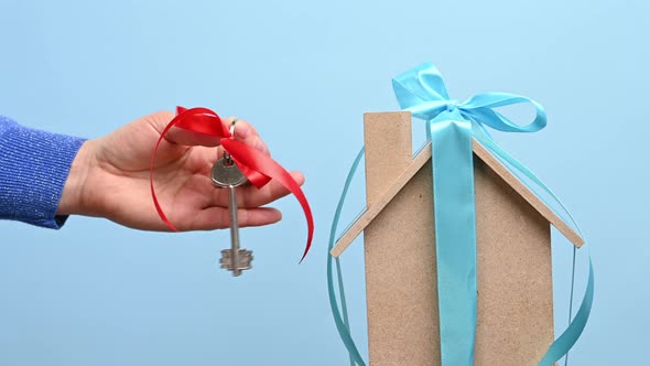 female hand holds a metal key with a red ribbon alt
