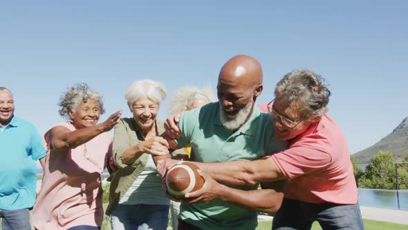 Happy senior diverse people playing rugby in garden at retirement home alt