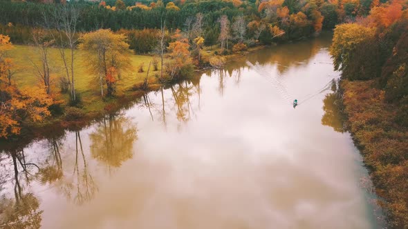 Gorgeous aerial footage of the colorful, autumn foliage along a river on a calm, October day alt