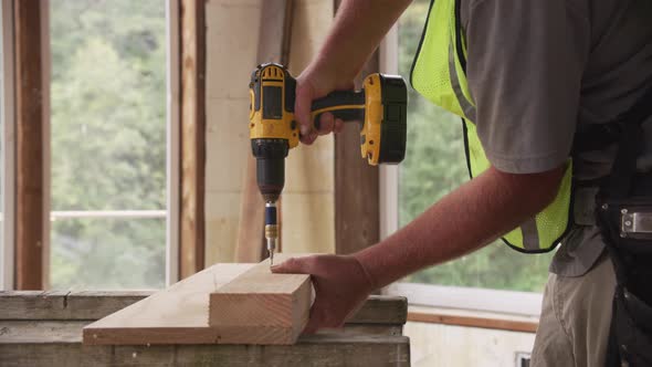 Construction worker using cordless screw gun alt