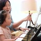 Asian mother and daughter practice piano together with happiness music class. - VideoHive Item for Sale