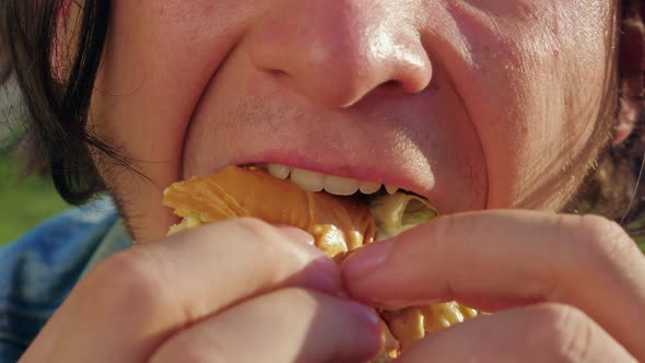A Man is Biting a Cheeseburger with Great Appetite alt
