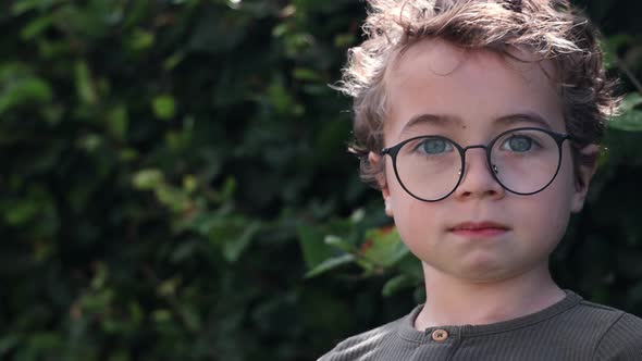 Cute kid with glasses looking at the camera with a neutral face