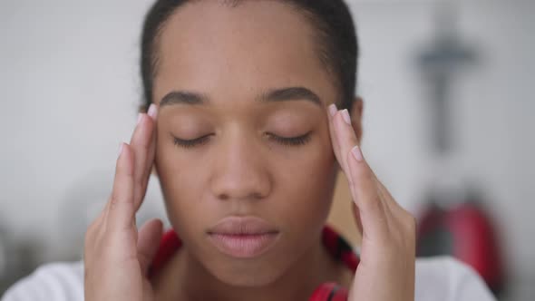 Closeup of Exhausted Overburdened African American Young Woman with Migraine Rubbing Temples Looking alt