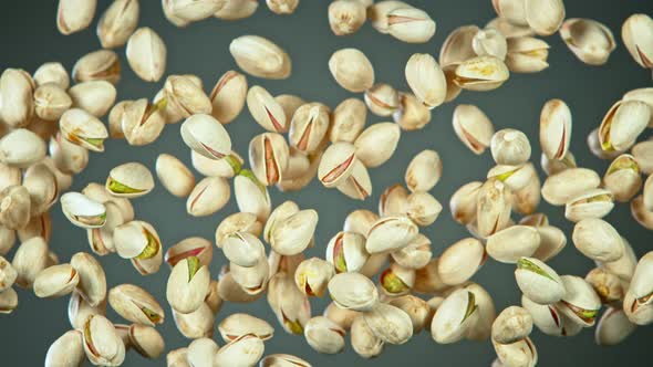 Super Slow Motion Shot of Flying Pistachios After Being Exploded on Grey Background at 1000Fps alt