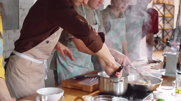 Chef Cooking Pasta with Assistance of Students during Culinary Class alt
