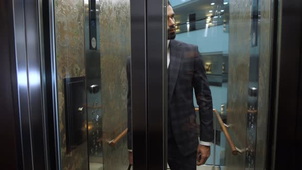 Confident Businessman Exiting Hotel Elevator alt