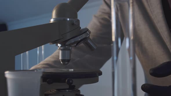 Closeup of a Man in a Laboratory Setting Up a Microscope Over a Glass Slide alt