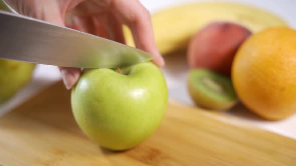 Female Hands Cutting Apple with a Knife on a Wooden Cutting Board