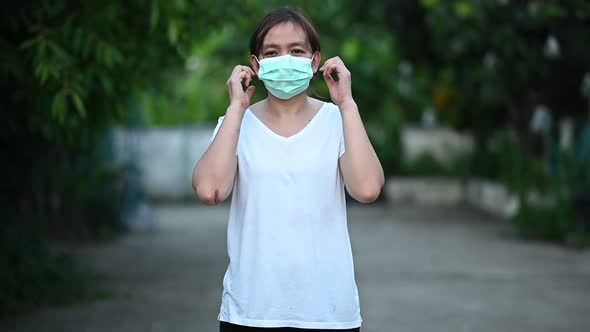A woman wearing a white T-shirt is taking off a medical mask.Slow motion footage.
