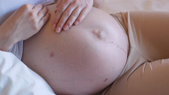 A woman expecting a baby is stroking her bare belly. Pregnancy and childbirth.