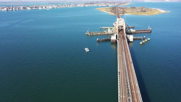 A high angle shot over elevated train tracks crossing a bay in Queens, NY. The camera dolly in over alt
