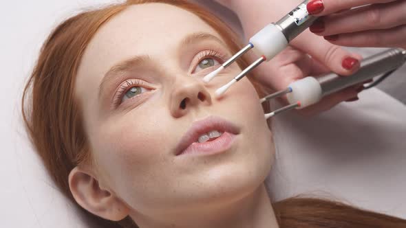 A Young Redhaired Woman in the Cosmetologist's Office Receives a Microcurrent Procedure