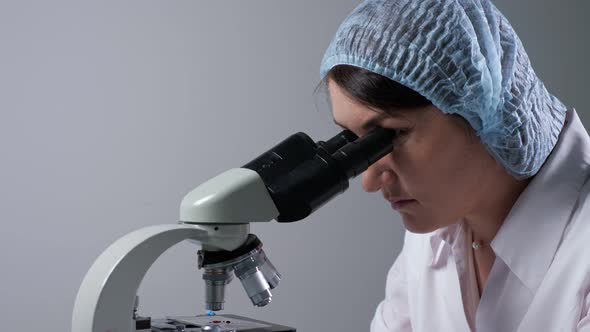 Lab Assistant Looks at Material Sample Through Microscope alt