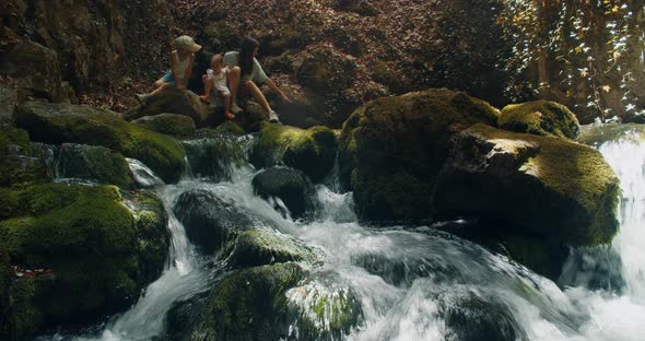 Mother with Children Rest on Mountain River During Summer Hike Journey alt