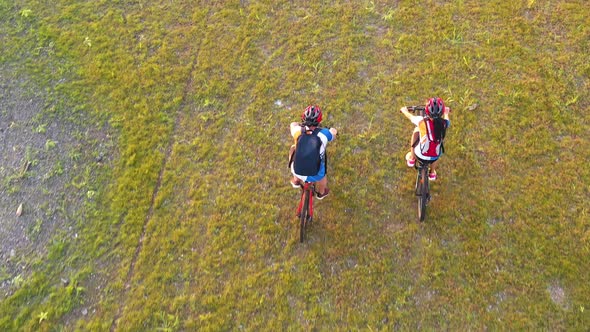 Footage B Roll 4k. Aerial view Drone tracking young People riding a bikes on the meadow