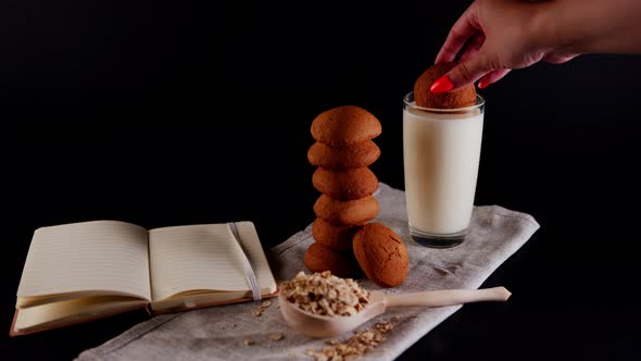 Oatmeal Cookies Laid Out in a Stack a Woman's Hand Soaks Cookies in a Milk Glass alt