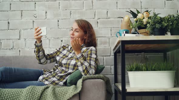 Beautiful Woman Is Chatting with Friends Looking at Smartphone Screen and Talking with Happy Smile alt