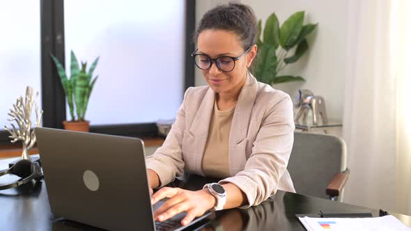 Concentrated Young Office Worker Businesswoman in Glasses Sitting at the Desk in the Office