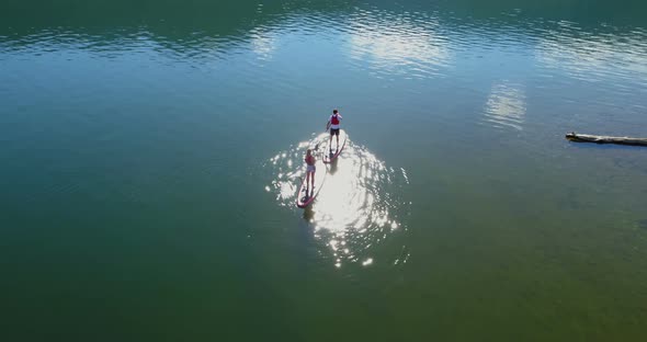 Couple on stand up paddle board oaring in river 4k alt