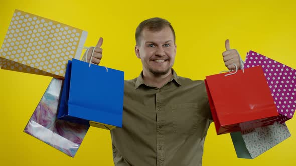 Man Raising Shopping Bags, Looking Satisfied with Purchase, Enjoying Discounts on Black Friday alt