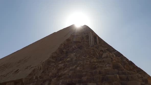 Eroded Bent Pyramid in Dahshur, Egypt with the sun shining at the top. alt