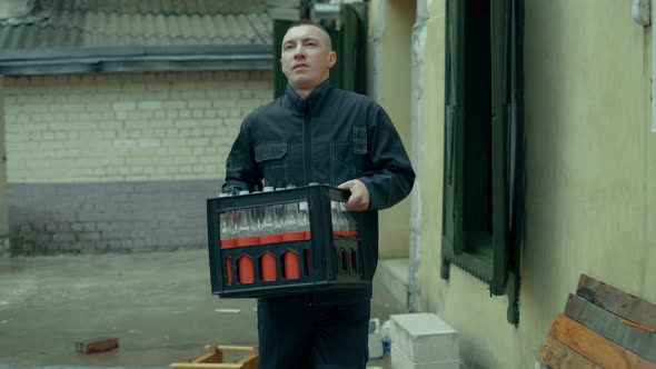 A Worker in Uniform is Carrying Cargoto the Warehouse