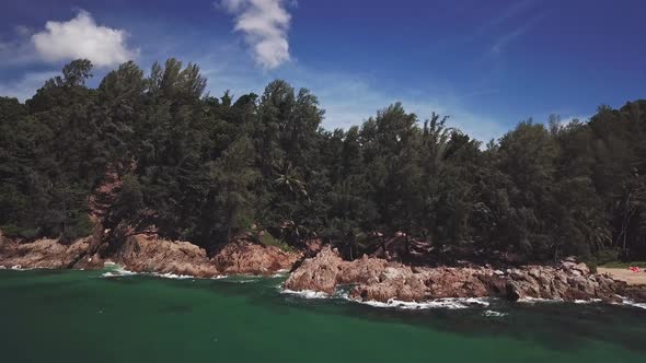 Aerial view of the tropical and rocky beach, waves crashing on rocks. Thailand.