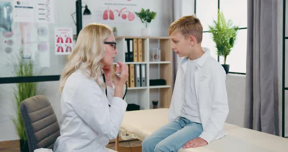 Female Pediatricain Examining Heartbeat and Lungs of  Boy During Scheduled Visit to Clinic alt