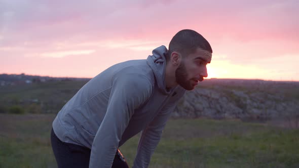 Exhausted Sportsman Drinking Water After Workout in Field