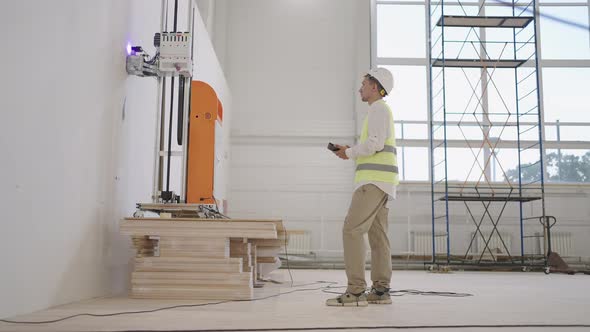 A Software Engineer Adjusts the Operation of the Robot for Laser Printing on the Wall alt