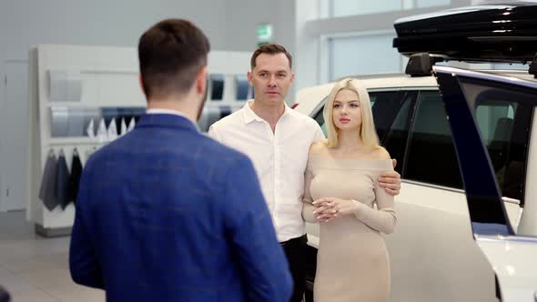Portrait Couple Talking to Car Dealer in Dealership Discussing the Chosen Car alt