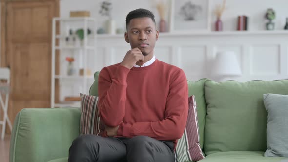 African Man Thinking while Sitting on Sofa alt