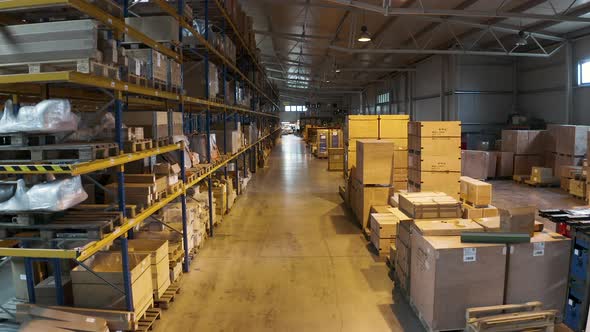 Warehouse aisles 13 and 14 with stacked cardboard boxes,racks,pallets. alt